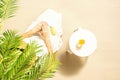 Alone woman applying sunscreen for protection skin sitting under palm tree branches near beach table with orange juice. Top view. Royalty Free Stock Photo