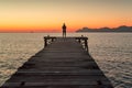 Alone woman standing on the pier by the sea in summer sunrise landscape