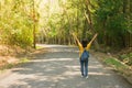 Alone woman traveller or backpacker walking along contryside road among green trees, she has feeling happiness.