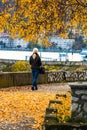 Alone woman walking on the autumn alley. Autumn landscape, orange foliage in a park in Orsova, Romania, 2020