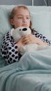 Alone worried child patient wearing oxygen nasal tube resting in bed holding teedy bear