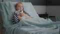 Alone worried child patient wearing oxygen nasal tube resting in bed holding teedy bear