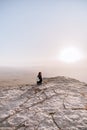 Alone young girl with backpack in israel negev desert admires the view of sunrise. Young female person stands on the edge