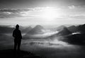 Alone young girl tourist feast autumn daybreak on the sharp corner of sandstone rock and watch over misty valley to Sun. Royalty Free Stock Photo