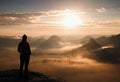 Alone young girl tourist feast autumn daybreak on the sharp corner of sandstone rock and watch over misty valley to Sun. Royalty Free Stock Photo