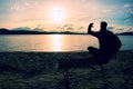 Alone Young Man In Silhouette Sitting In The Sun On Beach. Tourist take rest on wooden bench at autumn lake. Royalty Free Stock Photo