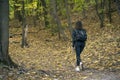 Alone young woman walking in the forest and enjoys autumn. Girl walks through wood, fallen leaves under feet Royalty Free Stock Photo