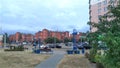 Along the city street are red brick buildings with metal roofs, trees, lampposts and parked cars. Nearby are paved sidewalks and b Royalty Free Stock Photo