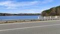 Along the shore of the lake is an asphalt road with markings and metal and concrete fences. There is mixed forest growing on the o Royalty Free Stock Photo