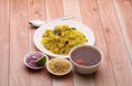 Aloo/Kanda Poha or Tarri Pohe with spicy chana masala/curry. Served in ceramic plate.