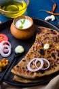 Aloo Paratha / Indian Potato Stuffed Wheat Bread served with Ghee Indian Butter, Curd & Pickle, Tomato & Onion. Top View.