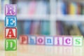 Alphabet blocks spelling the words read and phonics in front of a bookshelf Royalty Free Stock Photo