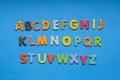 alphabet from bright colored paper letters on blue paper background. Royalty Free Stock Photo