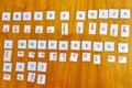 Alphabet in capitals and cursive letters on squares of paper used as teaching material for learning to read on a wooden table