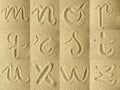 Alphabet handwritten in the sand Royalty Free Stock Photo