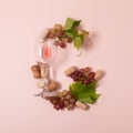 Alphabet. Letter G made of wineglasses with rose and white wine, grapes, leaves and corks lying on pink background. Wine Royalty Free Stock Photo