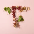 Alphabet. Letter T made of wineglasses with rose and white wine, grapes, leaves and corks lying on pink background. Wine Royalty Free Stock Photo