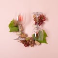 Alphabet. Letter U made of wineglasses with rose and white wine, grapes, leaves and corks lying on pink background. Wine Royalty Free Stock Photo