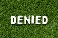 Alphabet in word denied on artificial green grass background