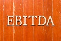 Alphabet in word EBITDA abbreviation of earnings before interest, taxes, depreciation and amortization on old red color