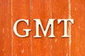 Alphabet in word GMT (abbreviation of Greenwich Mean Time) on old red color wood plate background
