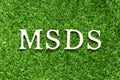 Alphabet in word MSDS Abbreviation of material safety data sheet on green grass background