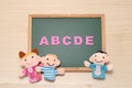 Alphabet letters ABCDE, children dolls and man doll on blackboard. English education concept. Royalty Free Stock Photo