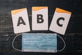 Alphabet letters cards and medical gauze mask on wooden table. Covid 2019, selfisolation, distant learning, home education