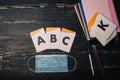 Alphabet letters cards, notebook, pencils and medical gauze mask on wooden table. Covid 2019, selfisolation, distant learning