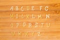 Alphabet pasta placed in alphabetical order on bamboo cutting board