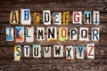 Alphabet set created with broken pieces of vintage car license plates on wood planks background