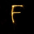 Alphabet sparklers on black background single letter