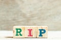 Alphabet in word RIP abbreviation of rest in peace on wood background