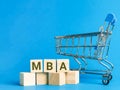 Alphabets MBA - Master of Business Administration on wooden cubes with miniature trolley.