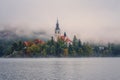 Alpine Bled lake (Blejsko jezero) in dense fog, amazing misty landscape, Slovenia, outdoor travel background