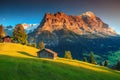 Alpine chalets with green fields and high mountains at sunset Royalty Free Stock Photo