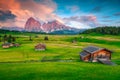 Alpine green fields and wooden chalets at sunset, Dolomites, Italy