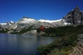 Alpine lake small red roof small house and dramatic gray rock snow mountains, Fantastic view of Jakob lagoon