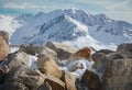 Alpine landscape with rocks at the front, peaks covered by snow and clouds, beautiful colors at the top of a glacier Royalty Free Stock Photo