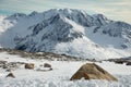 Alpine landscape with rocks at the front, peaks covered by snow and clouds, beautiful colors at the top of a glacier Royalty Free Stock Photo