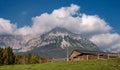 Alpine landscape on a sunny day. Colorful autumn scene. Mountain and a huge cloud above it. In the foreground is a relay