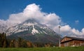 Alpine landscape on a sunny day. Colorful autumn scene. Mountain and a huge cloud above it. In the foreground is a relay