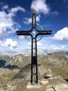 Mountain peak cross with cloudy blue sky in the background