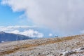 Alpine plateau covered with white stones, and a couple of hikers in the distance