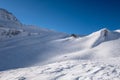 Alpine refuge below mountain ridge in winter on windswept snow Royalty Free Stock Photo