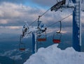 Alpine resort ski lift with seats going over the sunset mountain skiing  slopes in extremally windy weather Royalty Free Stock Photo