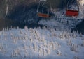 Alpine resortr ski lift with seats going over the sunset mountain skiing freeride slopes and fir tree groves Royalty Free Stock Photo