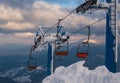 Alpine resortr ski lift with seats going over the sunset mountain skiing  slopes in extremally windy weather Royalty Free Stock Photo