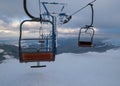 Alpine resortr ski lift with seats going over the sunset mountain skiing  slopes in extremally windy weather Royalty Free Stock Photo