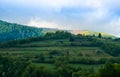 The alpine ridges of the Carpathian Mountains are surrounded by centuries-old forests on the background of the blue sky with white Royalty Free Stock Photo